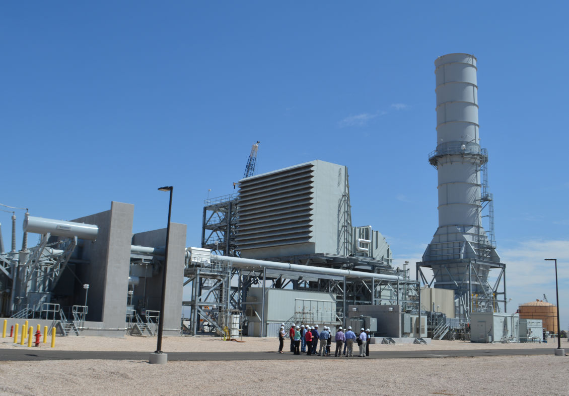Tour group standing beside a large simple-cycle turbine unit at Elk Station in Texas